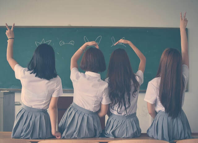 4 school children facing a blackboard